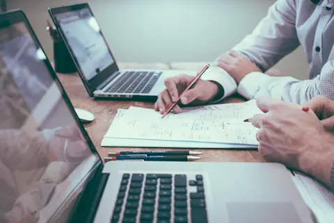 Due persone al tavolo con computer e appunti durante una consulenza