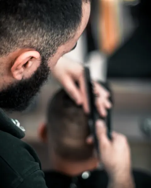 Barbiere che rifinisce un taglio con la macchinetta